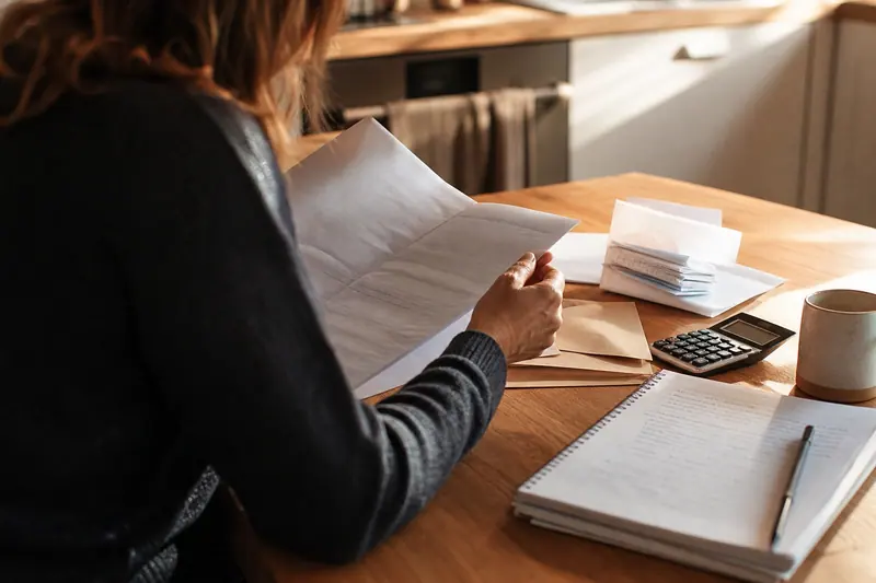 Personne comparant un contrat de prêt et son budget sur une table.